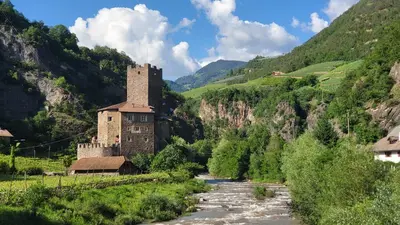 a castle in the mountains next to a river at Bolzano 2-Room Central Mountain View, WiFi Netflix AC Lift in Bolzano