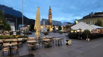 a group of tables and chairs in front of a building at Bolzano 2-Room Central Mountain View, WiFi Netflix AC Lift in Bolzano