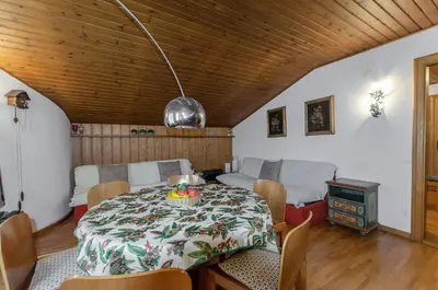 a dining room with a table and chairs and a room with a stove at Spazioso appartamento centrale con wi-fi in Cortina dʼAmpezzo