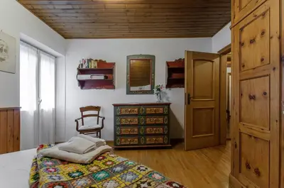a bedroom with a bed and a dresser and a chair at Spazioso appartamento centrale con wi-fi in Cortina dʼAmpezzo