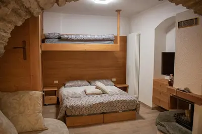 a bedroom with two beds and a flat screen tv at Busc De Crodol in Comune Rivamonte Agordino