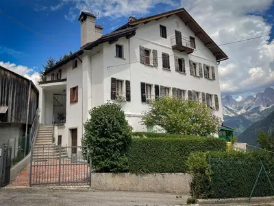 a white house with mountains in the background at Busc De Crodol in Comune Rivamonte Agordino
