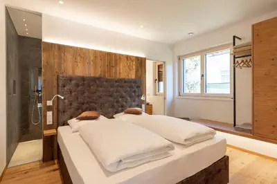 a bedroom with a large bed and a shower at Erbacher Living Nature Apartments Suites in Bolzano
