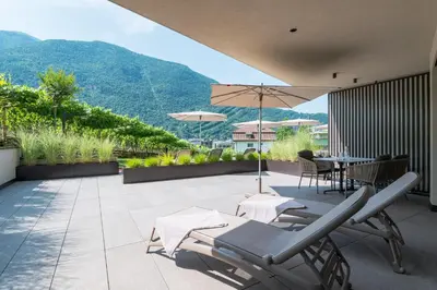 a patio with chairs and a table and an umbrella at Erbacher Living Nature Apartments Suites in Bolzano