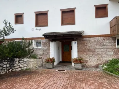 a white building with a door and a brick driveway at Sorapis Mini - Monolocale Panoramico in Cortina dʼAmpezzo