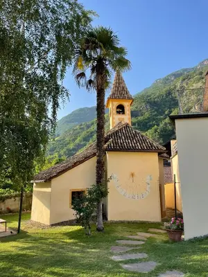 a church with a palm tree in front of a building at Gschnoferhof Terlan in Terlano