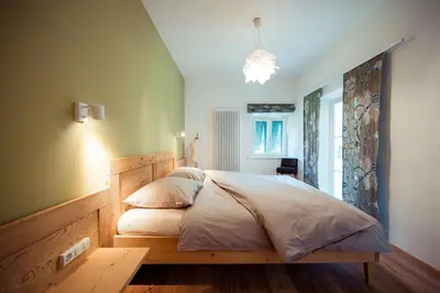 a bedroom with a large bed with a wooden headboard at Gschnoferhof Terlan in Terlano