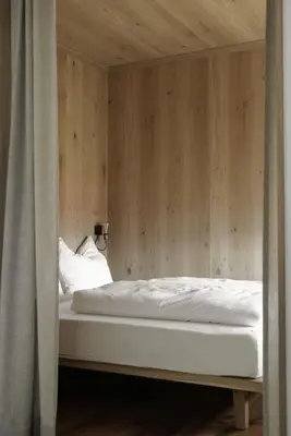 a bed in a room with a wooden wall at Kaiserau-Höfl in Bolzano