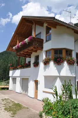 a white building with flowers on the windows at Apartment Christian in Nova Levante