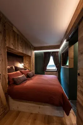 a bedroom with a bed with a red comforter and a window at Cortina Center House in Cortina dʼAmpezzo