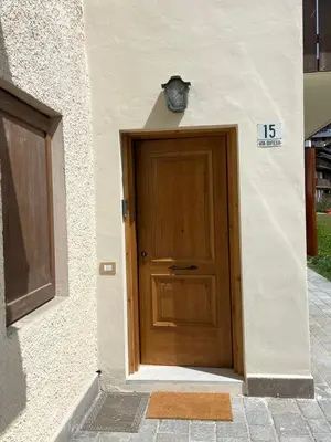 a door to a building with a clock on top at Cortina Center House in Cortina dʼAmpezzo