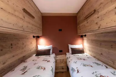 two beds in a room with wooden walls at Cortina Center House in Cortina dʼAmpezzo