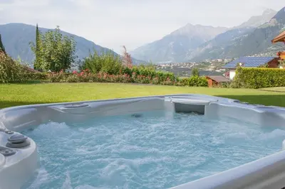 a hot tub in a yard with mountains in the background at Hotel Garni Katnau in Schenna