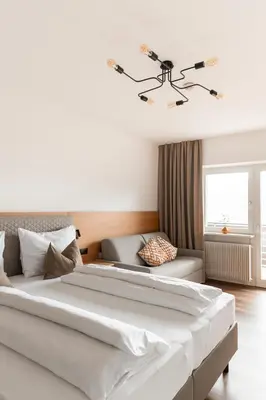 a bedroom with a large white bed and a couch at Hotel Garni Katnau in Schenna