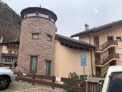 a building with a stone tower in front of it at Pragma Apartments - Appartamento La Torre in Predazzo
