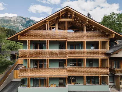 a large house with wooden balconies on the side of it at Max Green Forest Apartments in Siusi