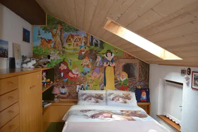 a bedroom with a bed with a painting on the wall at B&B La Tana dell'Orso - Die Bärenhöhle in Castello di Fiemme