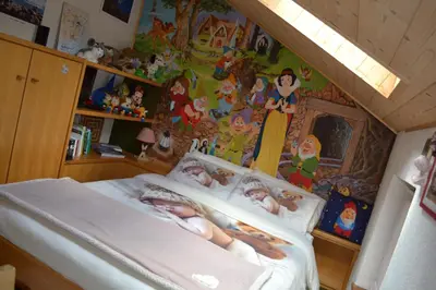 a bedroom with a bed with two babies laying on it at B&B La Tana dell'Orso - Die Bärenhöhle in Castello di Fiemme