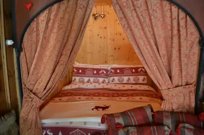 a bed with a canopy with a dog on it at B&B La Tana dell'Orso - Die Bärenhöhle in Castello di Fiemme