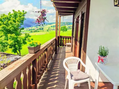 a wooden balcony with a white chair and a table at Vidora Apartments - Dolomites Escape in Alpe di Siusi (Seiser Alm) in Fiè