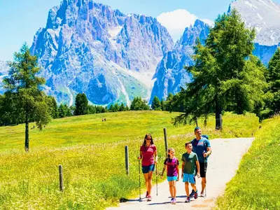 a family walking down a path in the mountains at Vidora Apartments - Dolomites Escape in Alpe di Siusi (Seiser Alm) in Fiè