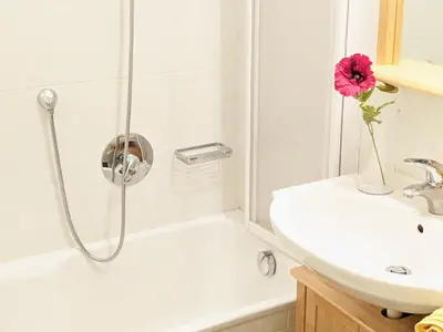 a bathroom with a shower with a vase with a pink flower at Vidora Apartments - Dolomites Escape in Alpe di Siusi (Seiser Alm) in Fiè