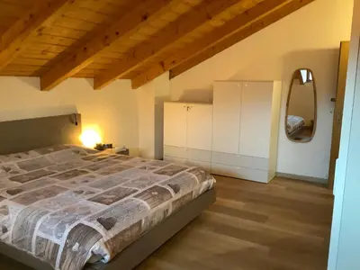 a bedroom with a large bed and a mirror at Passione Dolomiti in Romeno