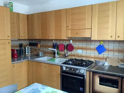 a kitchen with wooden cabinets and a stove top oven at Passione Dolomiti in Romeno