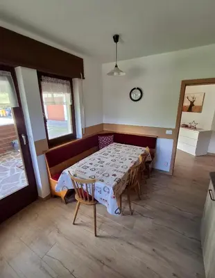 a dining room with a table and chairs and a clock at Falcade Dolomiti La Quiete piano terra in Fregona