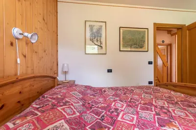 a bedroom with a bed and two pictures on the wall at Condominio Orsa Maggiore 12 in Falcade