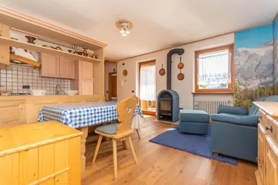 a kitchen and living room with a table and chairs at Condominio Orsa Maggiore 12 in Falcade