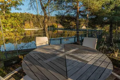 a wooden table and chairs on a deck with a lake at La Villa del Barone in Predaia