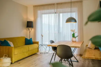 a living room with a yellow couch and a table at Auszait Apartments 1 in Caldaro