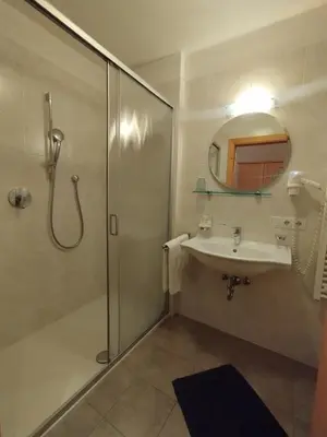 a bathroom with a shower and a sink and a mirror at romy's B&B in Braies