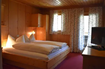 a bedroom with a bed with white sheets and a television at romy's B&B in Braies
