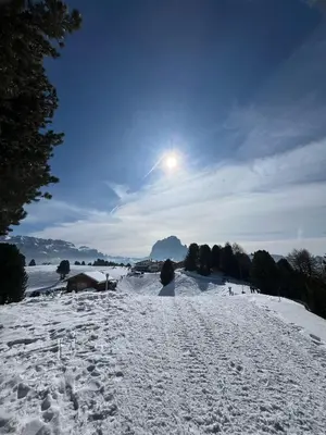 a snow covered slope with the sun in the sky at Gardena SudTirol Gianni's Home in Santa Cristina in Val Gardena