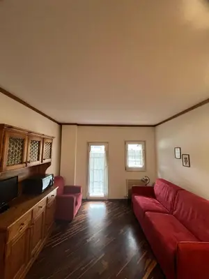 a living room with a red couch and a tv at Gardena SudTirol Gianni's Home in Santa Cristina in Val Gardena