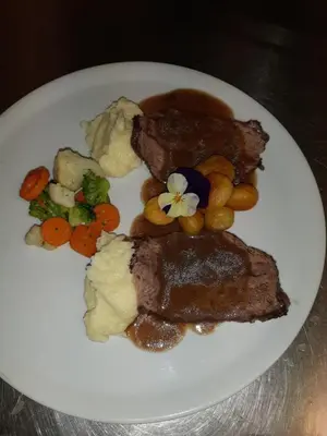 a plate of food with meat and vegetables on a table at Albergo Scoiattolo in Tret