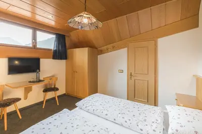 a bedroom with a bed and a desk and a television at B&B Ciauceia in Selva di Val Gardena