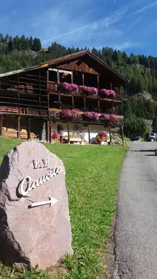 a building with a clock on a rock in front of it at B&B Ciauceia in Selva di Val Gardena