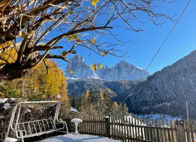 a chair on a porch with a view of mountains at B&B Ciauceia in Selva di Val Gardena