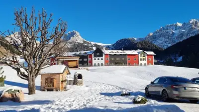 a building in the snow with a car parked in front at B&B Ciauceia in Selva di Val Gardena