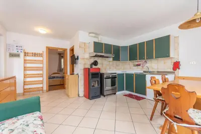 a kitchen with green cabinets and a table in it at Residenza al Villaggio in Mazzin