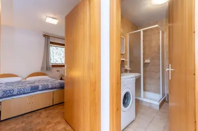 a small bedroom with a bed and a washing machine at Residenza al Villaggio in Mazzin