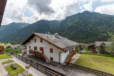 a small white house with mountains in the background at Residenza al Villaggio in Mazzin