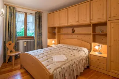 a bedroom with a large bed with wooden cabinets at Cozy apartment near Cortina in San Vito di Cadore
