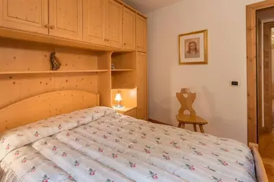 a bedroom with a large bed with a wooden headboard at Cozy apartment near Cortina in San Vito di Cadore