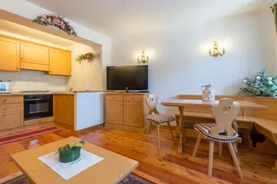 a large kitchen with a table and a tv in it at Cozy apartment near Cortina in San Vito di Cadore