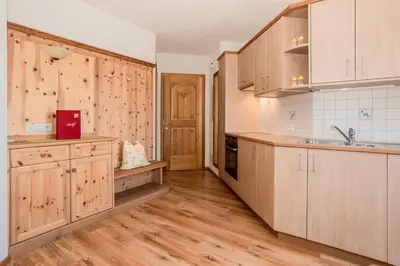 a kitchen with wooden cabinets and wooden floors at Leishof in Villandro