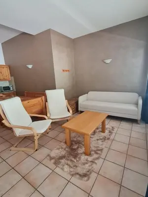 a living room with two white chairs and a coffee table at Appartamento El Feudo in Tesero